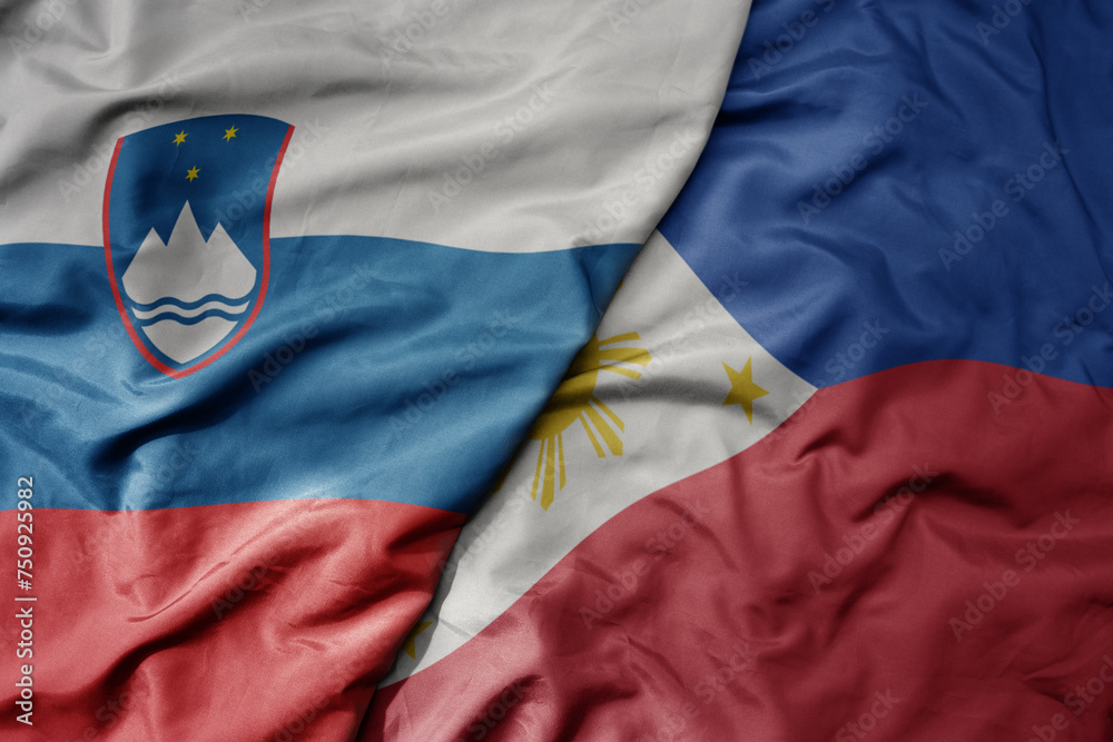 Fototapeta premium big waving national colorful flag of philippines and national flag of slovenia.
