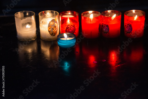 Catholic prayer candles, with Holy Family and Mary with baby Jesus, glow in darkness in church. Christmas holiday celebration background.