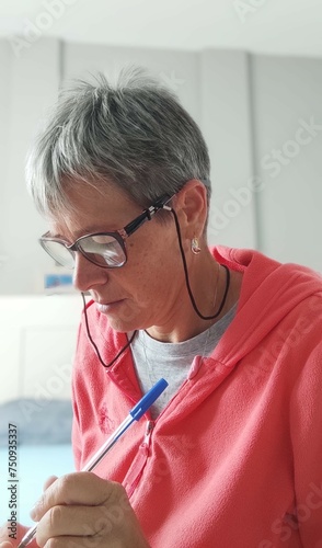 Tableau sur toile profile of mature woman, with eyeglasses, writing concentrated, in the bedroom