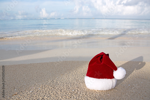 Christmas background with red Santa hat on the white Caribbean sand.