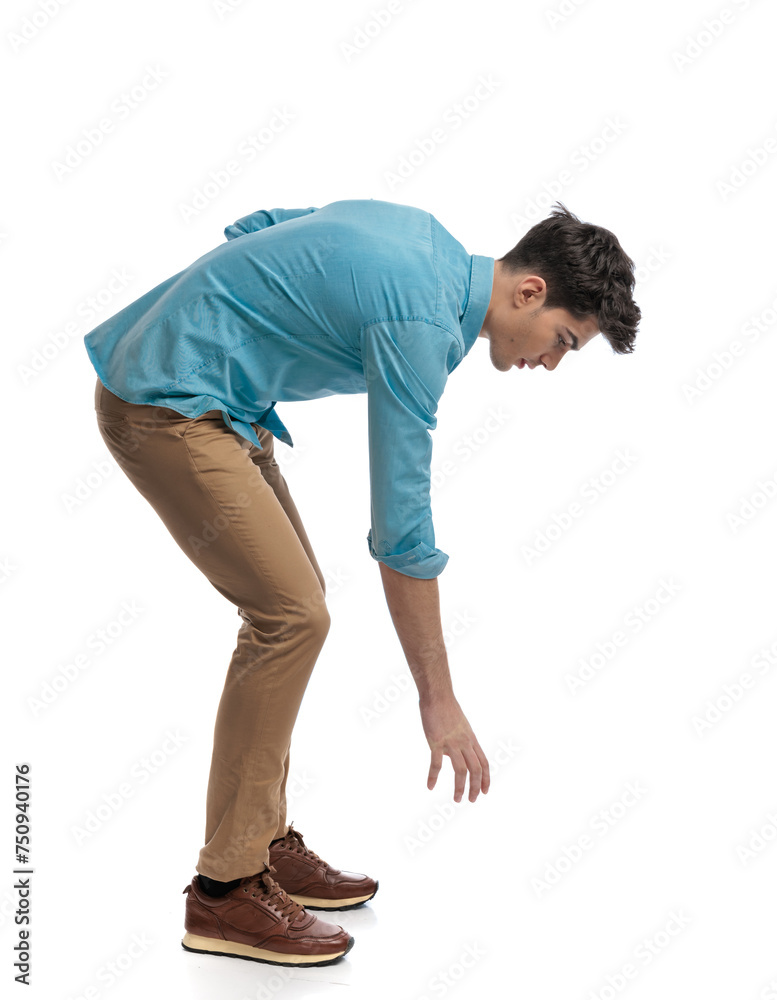 side view of casual man picking something up side view of casual man picking something up