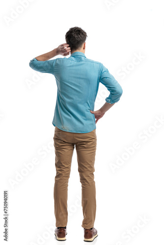 back view of puzzled casual man scratching his head
