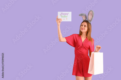 Young woman in bunny ears with shopping bags and card on lilac background. Easter celebration