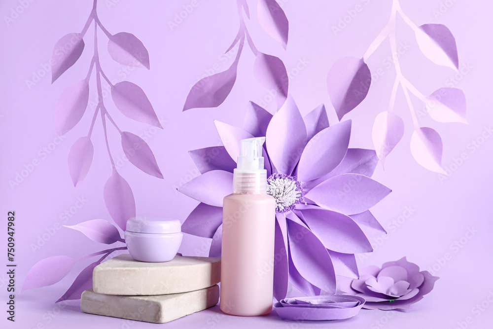 Skin care cosmetics and paper flowers on lilac background Skin care cosmetics and paper flowers on lilac background