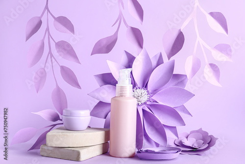 Skin care cosmetics and paper flowers on lilac background