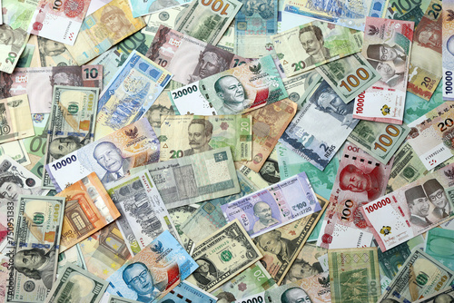 Many banknotes of different currency. Background of big amount of random money bills close up photo