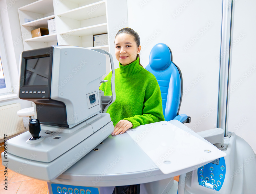 A woman with a green sweater sits in front of an output device