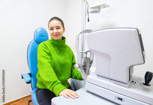 a woman in a green sweater is sitting in a blue chair in front of a machine photo