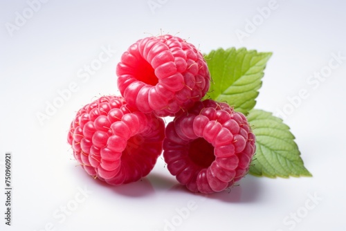 Three red raspberries on a leaf