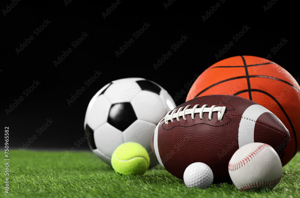 Many different sports balls on green grass against black background, space for text
