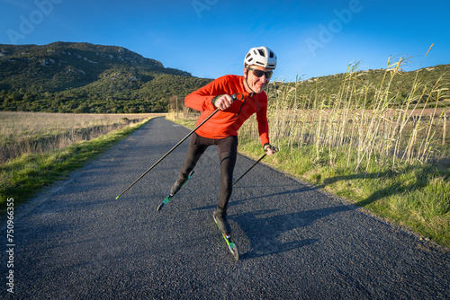 un skieur sur des ski-roues en pleine campagne  sur une route goudronnée