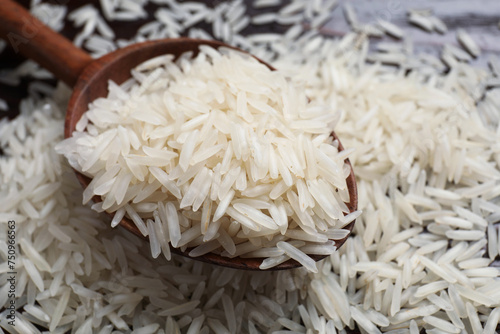 Raw basmati rice and wooden spoon on table, closeup