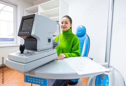 Woman in green sweater using computer at table with monitor photo