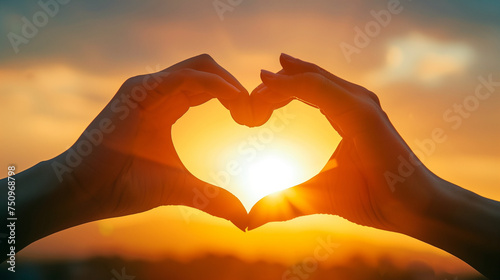 Silhouette of Hands Shaping Heart Against Sunset, Symbol of Love and Connection in Golden Evening Light
