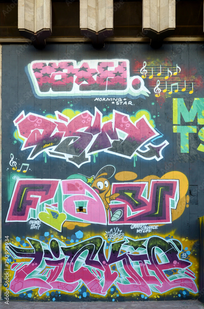 The old wall decorated with paint stains in the style of street art culture. Colorful background of full graffiti painting artwork with bright aerosol outlines on wall. Colored background texture The old wall decorated with paint stains in the style of street art culture. Colorful background of full graffiti painting artwork with bright aerosol outlines on wall. Colored background texture