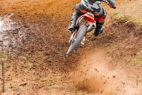 Rider on motocross bike navigating muddy offroad track with a helmet
