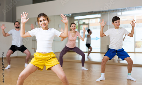 Cheerful girl exercising in family group during dance class at dance studio