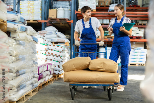 Young woman and young guy in uniform check documents in warehouse