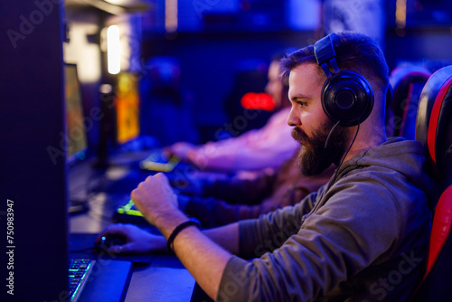 Young bearded man gamer with headphones playing video games in an internet cafe © Zamrznuti tonovi