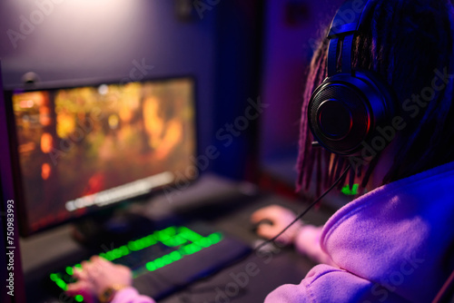 Rear view of a esport gamer wearing headphones and playing online video game