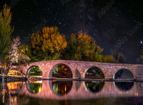 puente antiguo sobre rio en noche estrellada photo