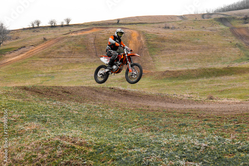 Motorcycle racer with helmet rides motocross bike on dirt track