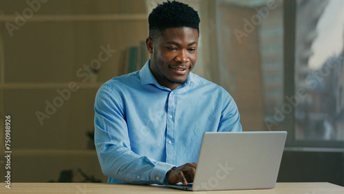 Smiling African American businessman use computer at office. Male professional manager typing on laptop business man smile writing e-mail message surfing internet working on e-commerce startup project