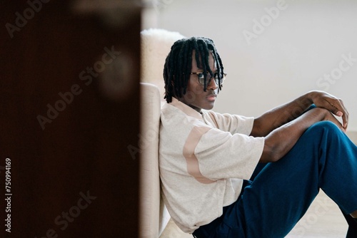 Man with dreadlocks wearing vintage clothing sitting on the floor at home