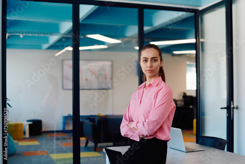 Portrait of a business woman in a creative open space coworking startup office with crossed arms. Successful businesswoman standing in office with copyspace. Associates work in the background