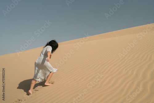 Woman running up the dune in the desert