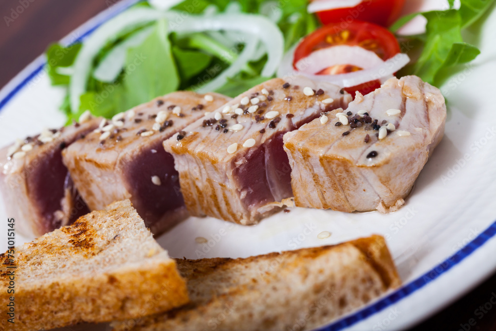 Picture of tasty lightly fried tuna, served at plate with bread and greens