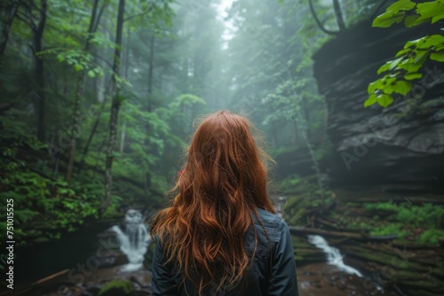 Woman with Red Hair Standing Before Lush Forest Waterfall, Surrounded by Mist and Greenery in Serene Nature Setting photo