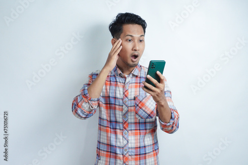 Adult Asian man looking to his mobile phone with wow expression photo