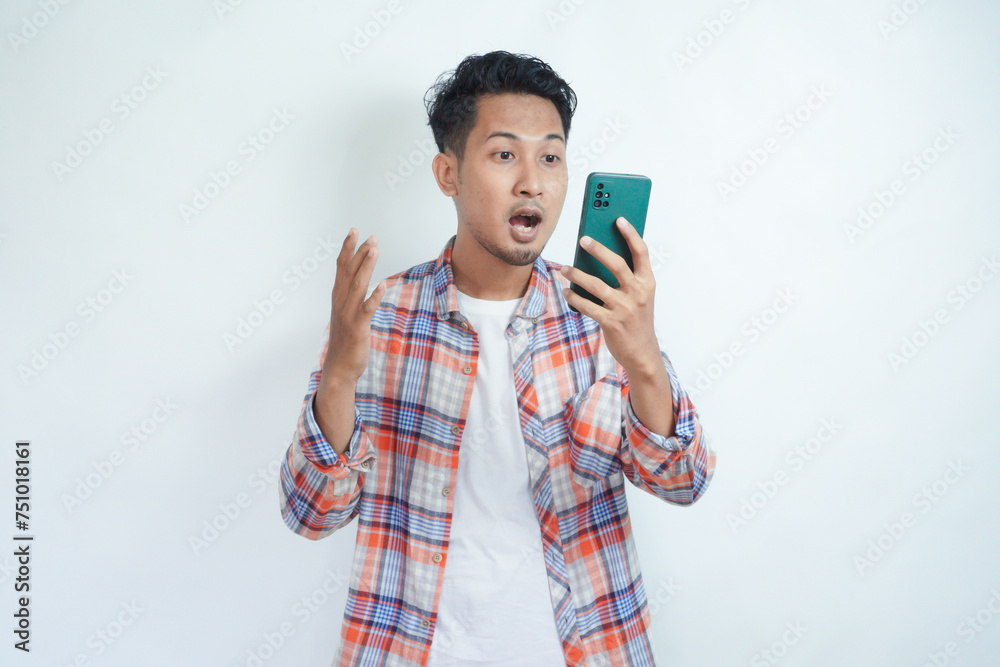 Adult Asian man looking to his mobile phone with wow expression Adult Asian man looking to his mobile phone with wow expression
