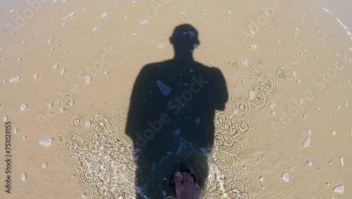Shadow of a man walking on the shore of the ocean