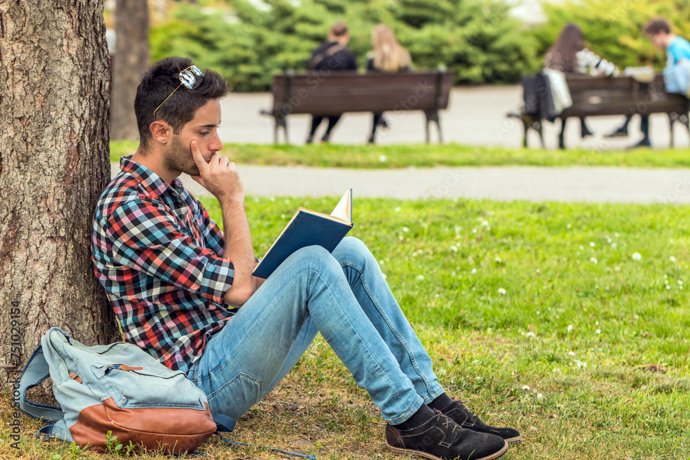 College student with book. Student guy doing homework in the park. College student with book. Student guy doing homework in the park.