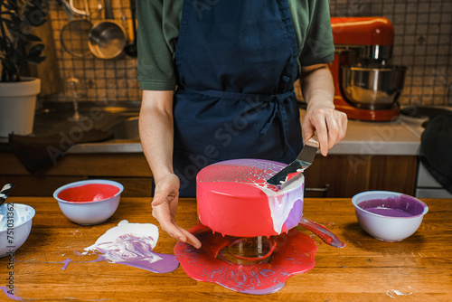 a pastry chef decorates an unusual mousse cake with icing at home photo