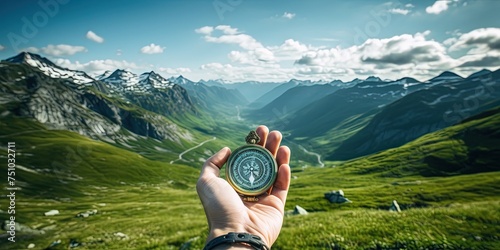 Compass in man's hand in front of summer mountain landscape with green hills and cloudscape , travel adventure and discovery consept