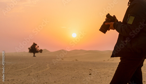 silhouette of a person with a camera in the desert against the backdrop of sunrise. dawn in the desert with a person with a camera in his hands in the foreground © serhii