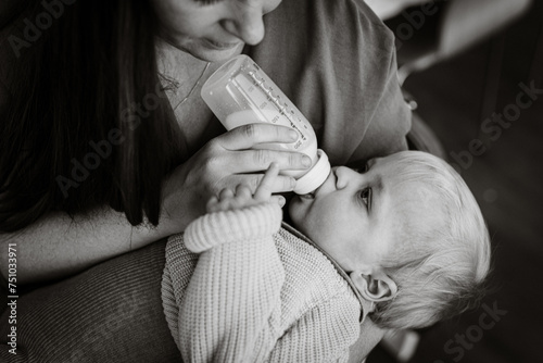 black and white image of Mother feeding milk in a bottle photo