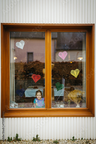 Birthday girl by the window. Kite paper hearts for decoration.