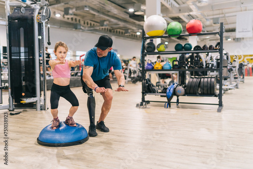 Girl exercising on bosu ball with disabled father photo