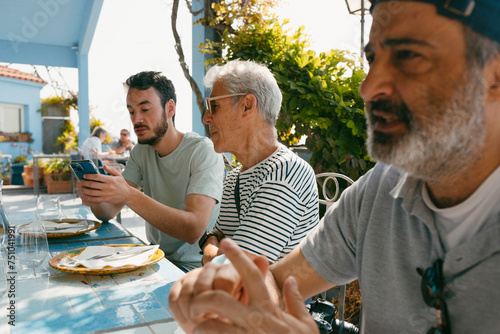 Men in outdoor restaurant looking at  smartphone photo