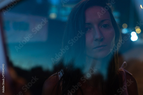 female portrait in night city, sad woman looking at camera