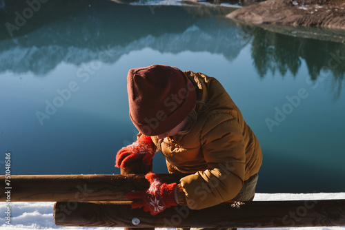 A kid collecting a snow by the lake photo