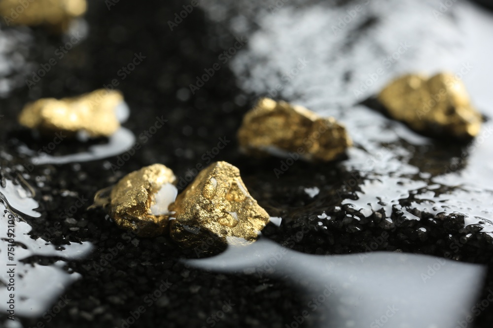 Shiny gold nuggets on wet stones, closeup Shiny gold nuggets on wet stones, closeup