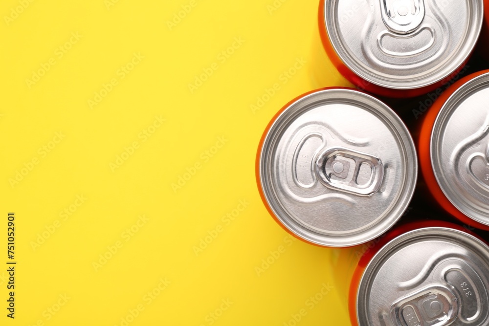 Energy drink in cans on yellow background, top view. Space for text Energy drink in cans on yellow background, top view. Space for text