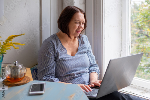 midle-aged woman working on laptop photo