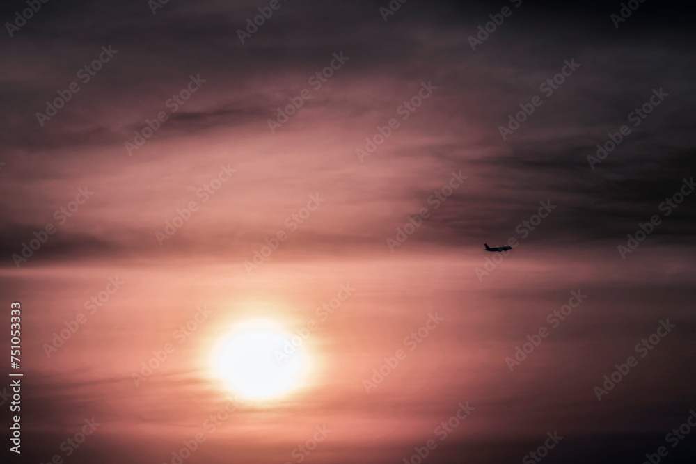 Airplane with cloudy sky at sunset
