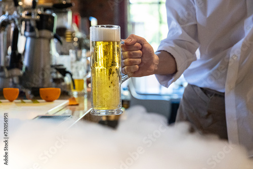 Anonymous bartender serve draft lager beer next to dry ice smoke  photo